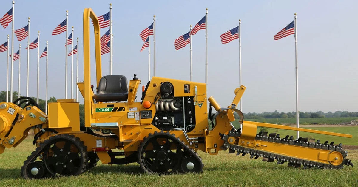 Vermeer PTX44 trencher on a Kentucky field with rows of American flags flying behind — West Coral Communications